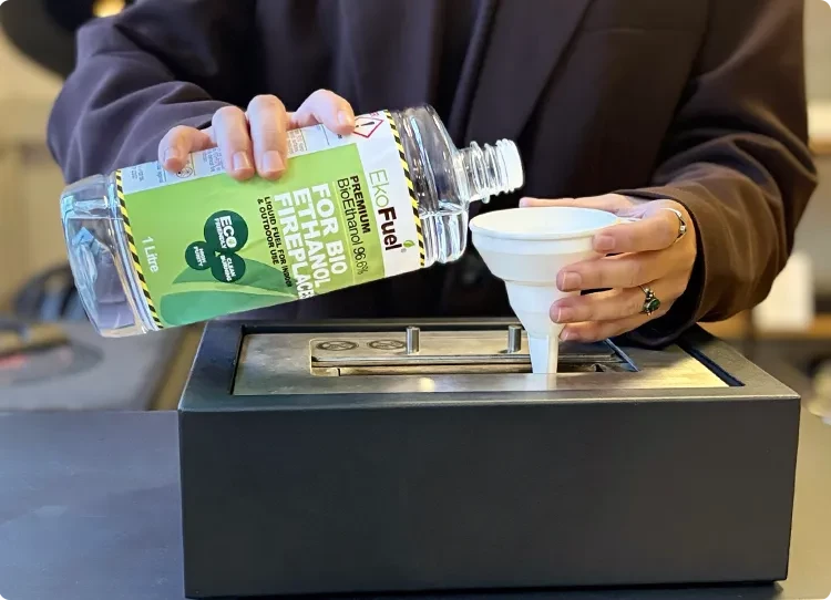 Bioethanol-Brennstoff wird mit einem Kunststofftrichter in einen Brenner gegossen